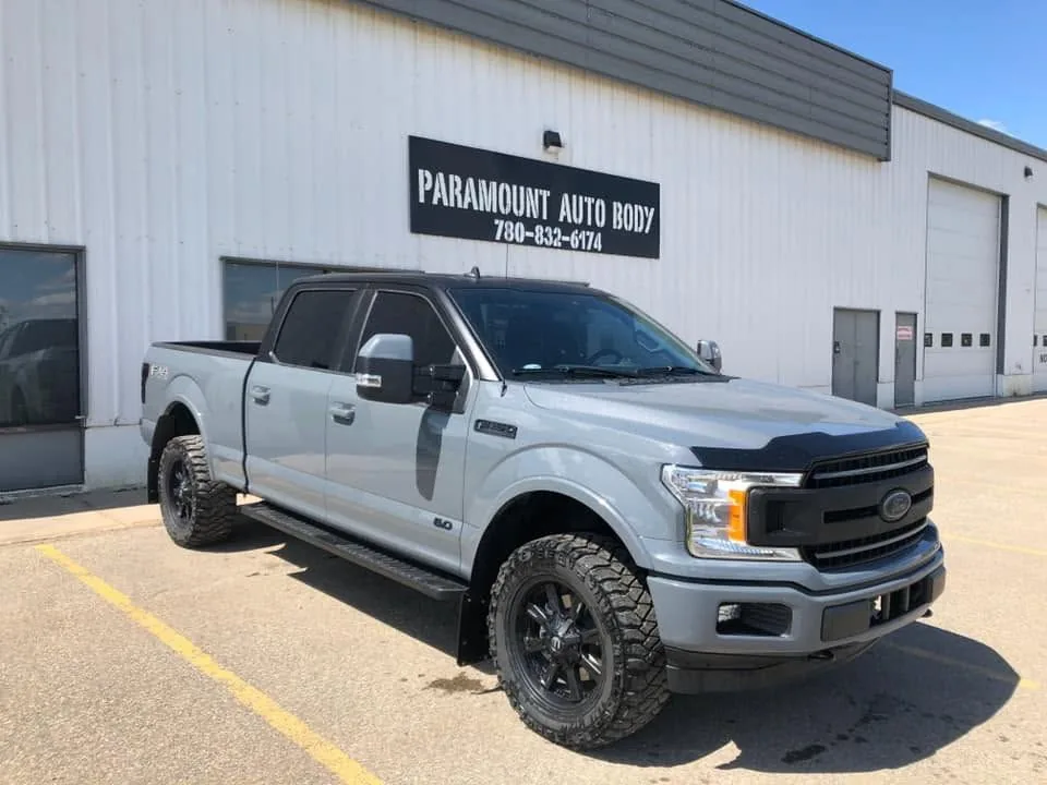Lifted Ford F-150 outside the Paramount Auto Body shop sign